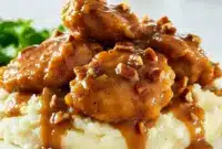 Maple Bourbon Pecan Chicken — Skillet Dinner Recipes in 30 Mins Close-up of glossy maple-bourbon chicken thighs on mashed potatoes, sauce pooling around the edges with chopped nuts visible — a Gluten Free Recipes For Dinner style plate with Iowa Girl Eats energy and a hint of Pollo Loco flair.