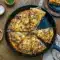 Overhead shot of a cheesy Pizza With Ground Beef topped with caramelized onions and melted cheddar in a cast iron skillet — a cozy Deep Dish Pizza Recipe inspired by a classic patty melt.
