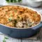 Golden, cheesy Baked Chicken Wild Rice Casserole in a white baking dish, topped with crispy panko breadcrumbs and garnished with fresh herbs.