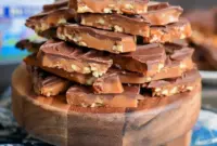 Close-up of broken toffee with toasted pecans and glossy chocolate, a sweet snack trending among Trending Desserts 2025, inspired by a light Sponge Toffee Recipe texture.