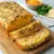 Golden loaf of homemade Easy Cheddar Bread sliced on a cutting board, showing melted cheese and soft texture—perfect Breads To Go With Soup or weeknight meals.