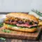 Close-up of a toasted steak sandwich layered with juicy sliced beef, garlic aioli, melted provolone, arugula, and caramelized onions, styled as a refined lunch plate with elegant sides.