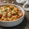 Golden cheesy chicken pieces layered over crispy roasted potatoes in a creamy garlic sauce, served hot in a rustic pan for a hearty, satisfying dinner.