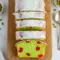Moist pistachio loaf studded with maraschino cherries, drizzled in glossy almond glaze and styled for a warm holiday dessert table.