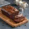 Close-up of thick slices of rich chocolate fudge brownie bread with glossy hot fudge swirls and a soft, moist center on a rustic wooden board, ready to serve and enjoy. 🍫