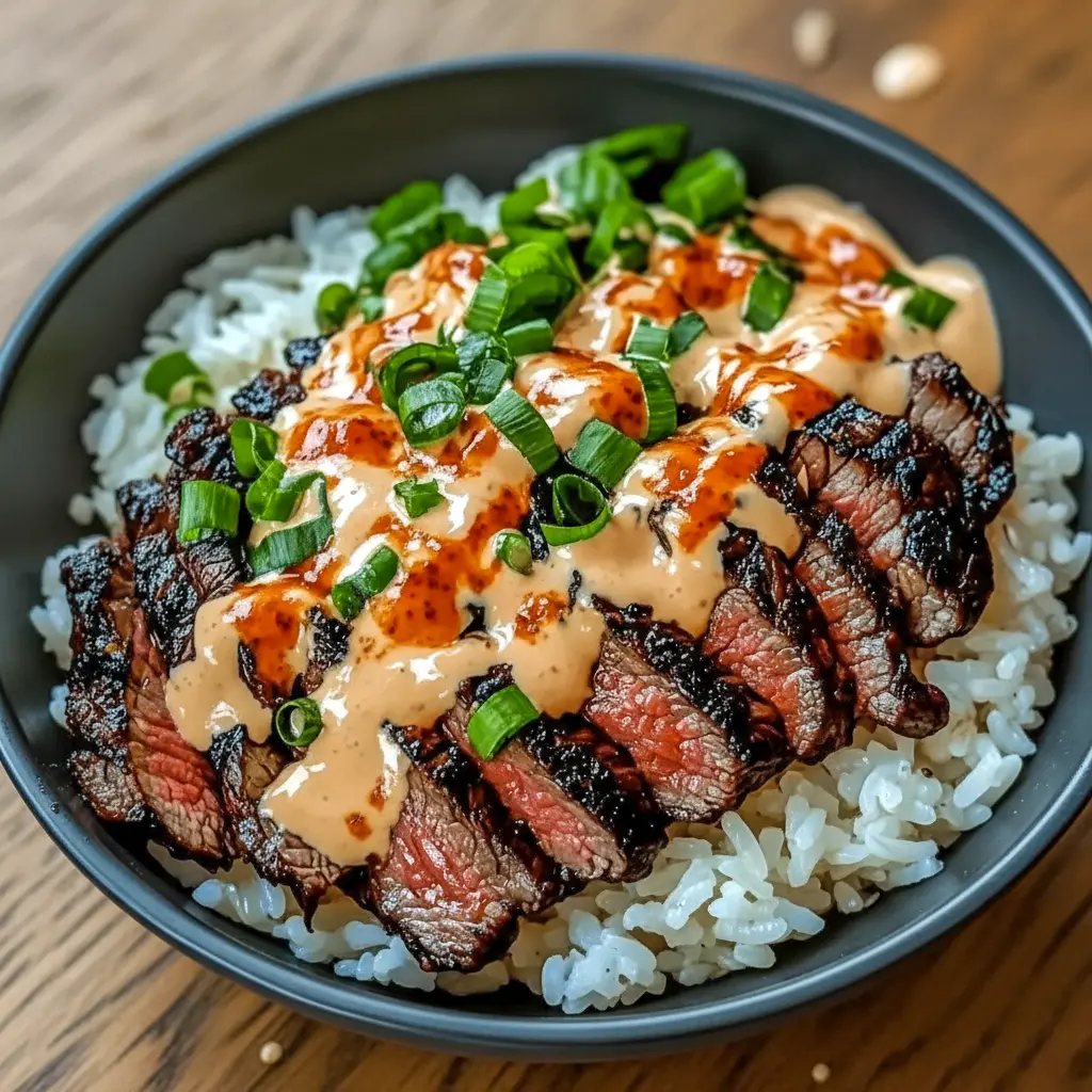 Addictive Korean BBQ steak and rice bowl featuring juicy sliced steak, fluffy rice, fresh vegetables, and a creamy spicy sauce for a bold, flavorful dinner.