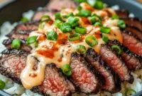 Addictive Korean BBQ steak and rice bowl featuring juicy sliced steak, fluffy rice, fresh vegetables, and a creamy spicy sauce for a bold, flavorful dinner.