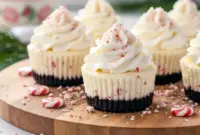 Mini no-bake peppermint cheesecakes with Oreo crust, whipped cream, and crushed peppermint candy sprinkled on top—festive holiday treats perfect for parties and Christmas gatherings.