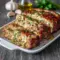 Garlic Parmesan chicken meatloaf sliced on a platter, topped with melted parmesan, surrounded by fresh herbs, showcasing a golden, tender texture perfect for an easy weeknight dinner.