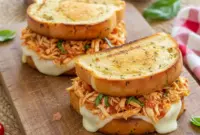 Delicious Shredded Italian Chicken Sandwiches for Effortless Meals2 Close-up of warm garlic-bread Italian Chicken Sandwiches stacked with tender Shredded Italian Chicken, melted provolone, fresh basil, and rich tomato-herb sauce.