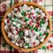 Bowl of sweet and crunchy holiday Reindeer Food Puppy Chow coated in powdered sugar with festive candies, perfect for Christmas snacking and winter dessert parties.