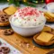 A bowl of creamy peppermint dessert dip topped with crushed candy pieces, styled for the holidays and served with chocolate cookies and pretzels, inspired by Jalapeno Popper Dip, Peppermint Cheesecake, classic Cheesecake Dip, and fun party favorites like Taco Dip.