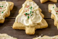 Plate of soft, frosted holiday cookies made with eggnog, decorated with festive sprinkles and inspired by Eggnog Cookies Christmas, Eggnog Cookies With Cream Cheese Frosting, Eggnog Snickerdoodles With Icing, Frosted Eggnog Cookie Recipe, Eggnog Cookies Recipe, Soft Holiday Eggnog Cookies, Glazed Eggnog Cookies Recipe Allrecipes, Frosted Eggnog Cookies, and Christmas Cookies Eggnog treats.