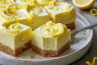 Best Triple Lemon Cheesecake Swirl Bars That Taste Unbelievable1 Triple Lemon Cheesecake Swirl Bars sliced and displayed on a tray, featuring creamy cheesecake layers with a vibrant lemon swirl, perfect for fans of Cheesecake Lemon Bars and elegant Flavored Cheesecake Recipes.