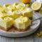Triple Lemon Cheesecake Swirl Bars sliced and displayed on a tray, featuring creamy cheesecake layers with a vibrant lemon swirl, perfect for fans of Cheesecake Lemon Bars and elegant Flavored Cheesecake Recipes.