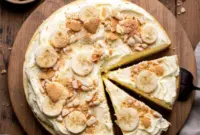 A slice of Banana Pudding Cheesecake With Wafers showing a creamy banana cheesecake filling, Nilla wafer crust, banana layers, and a light whipped pudding topping—an irresistible Banana Cheesecake With Nilla Wafers dessert perfect for parties and holidays.