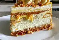 Banana Pudding Cookie Butter Cheesecake Cake layered with creamy cheesecake filling, crushed vanilla wafers, ripe bananas, and rich cookie butter, served as an indulgent no-bake dessert perfect for Family Dinner Dessert Ideas.