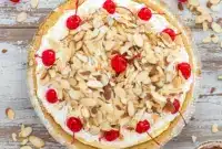 A slice of Cream Pies No Bake dessert showing a rich Almond Cream Pie with fluffy layers, toasted almond topping, and cherries, inspired by a classic Amaretto Pie Recipe and served chilled for a decadent no-bake finish.