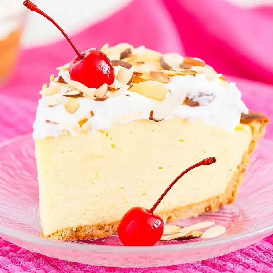A slice of Cream Pies No Bake dessert showing a rich Almond Cream Pie with fluffy layers, toasted almond topping, and cherries, inspired by a classic Amaretto Pie Recipe and served chilled for a decadent no-bake finish.