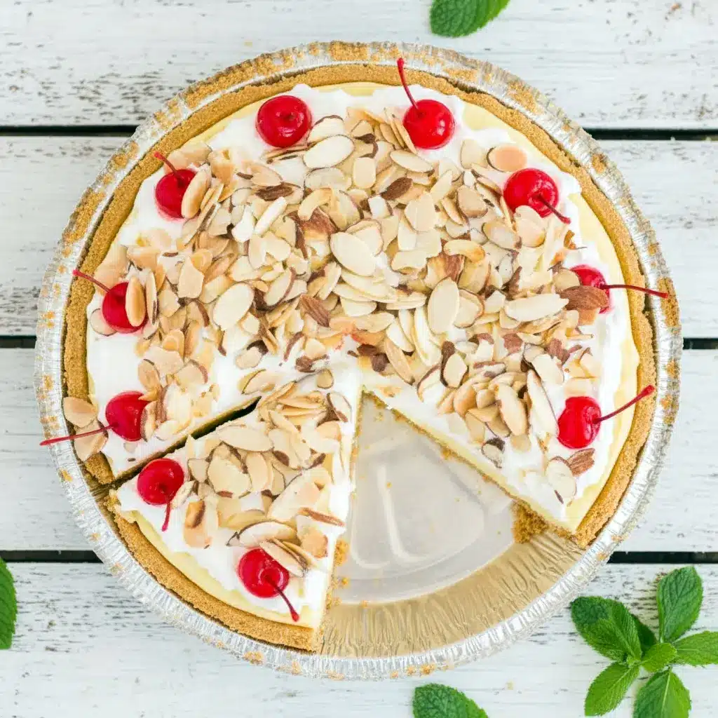 A slice of Cream Pies No Bake dessert showing a rich Almond Cream Pie with fluffy layers, toasted almond topping, and cherries, inspired by a classic Amaretto Pie Recipe and served chilled for a decadent no-bake finish.