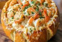 Creamy seafood soup loaded with shrimp served inside a crispy bread bowl, garnished with herbs and ready for a comforting homemade dinner.