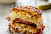 Golden chaffle stacked with corned beef, Swiss cheese, and sauerkraut, showcasing indulgent Keto Sandwich Ideas and crispy Keto Chaffles Low Carb sandwich perfection.