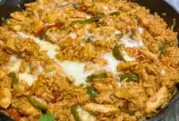 Hot Queso Skillet filled with seasoned chicken, colorful bell peppers, rice, and creamy melted queso, served straight from the pan for a rich, cheesy fajita-style dinner.