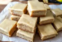 Freshly sliced Banana Dessert bars featuring soft Banana Bread Brownies with glossy brown butter frosting, showcasing a tender Banana Flavored crumb and golden edges on a serving platter.