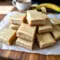 Freshly sliced Banana Dessert bars featuring soft Banana Bread Brownies with glossy brown butter frosting, showcasing a tender Banana Flavored crumb and golden edges on a serving platter.