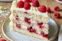 Beautiful White Chocolate Raspberry Dream Cake topped with raspberries and creamy frosting, a stunning Best Layered Cake and elegant choice for Birthdays Desserts and Cakes With Raspberry Filling lovers.