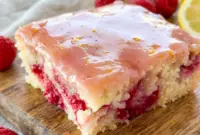 Freshly glazed Raspberry Lemonade Bars topped with bright lemon icing, a delicious Lemon Bar Dessert With Raspberries and one of the best Summer Raspberry Desserts for any occasion.