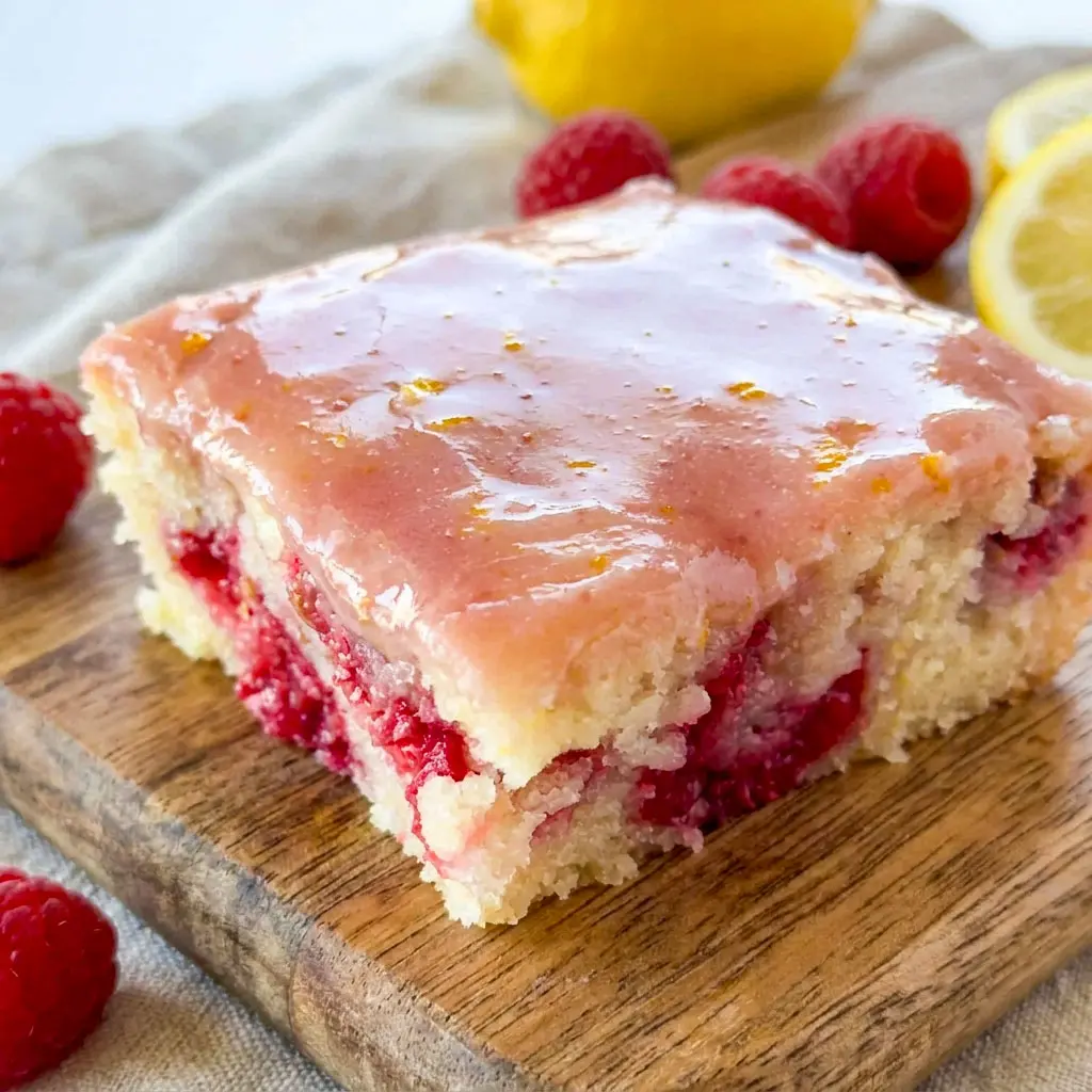 Freshly glazed Raspberry Lemonade Bars topped with bright lemon icing, a delicious Lemon Bar Dessert With Raspberries and one of the best Summer Raspberry Desserts for any occasion.