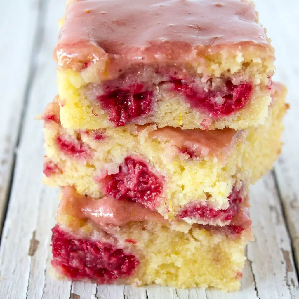 Freshly glazed Raspberry Lemonade Bars topped with bright lemon icing, a delicious Lemon Bar Dessert With Raspberries and one of the best Summer Raspberry Desserts for any occasion.