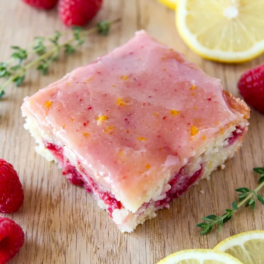 Freshly glazed Raspberry Lemonade Bars topped with bright lemon icing, a delicious Lemon Bar Dessert With Raspberries and one of the best Summer Raspberry Desserts for any occasion.