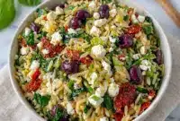 A bright bowl of Sundried Tomato Feta Orzo Salad with herbs and olives, perfect for Mediterranean Orzo Pasta Salad Recipes that taste fresh and satisfying.