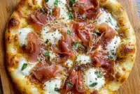 White Pizza with Prosciutto & Hot Honey for an Elevated Pizza Night A golden White Pizza with Prosciutto & Hot Honey topped with creamy cheese and crisp prosciutto, perfect for a homemade Specialty Pizza night.